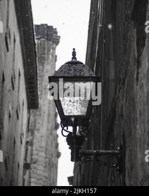 Photo verticale en niveaux de gris d'une vieille lampe humide sur le côté d'un bâtiment Banque D'Images