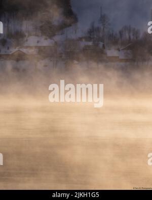 A vertical shot of the Lac de Joux lake covered with mist and smog in Switzerland Stock Photo