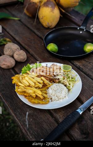 A beautiful shot of chicken, fries, rice and cabbage salad in a plate Stock Photo