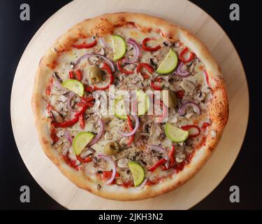 A top view of a pizza with zucchini, onion, mushroom, olives, pepper and cheese toppings Banque D'Images