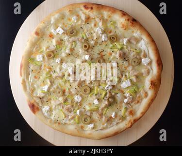 A top view of a pizza with olives, feta, chicken and zucchini toppings Stock Photo