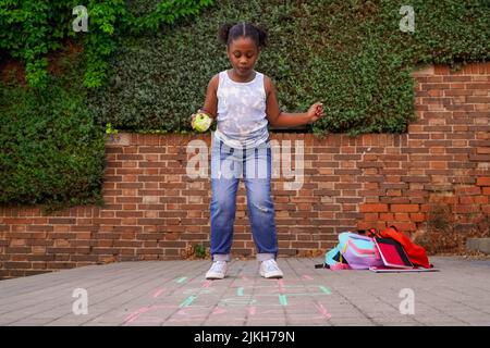 afro latino amercian fille hopscotch sur le terrain de jeu de l'école. retour à l'école concept. multiethnique groupe d'enfants Banque D'Images