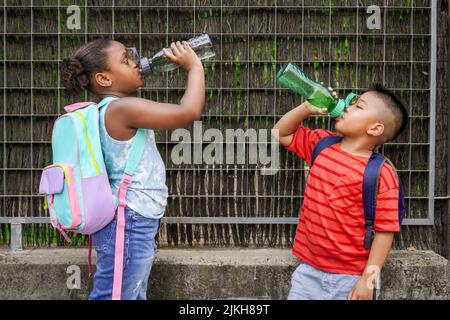 enfants multiethniques avec sacs à dos eau potable à l'entrée de l'école. Concept de retour à l'école. Fusillade de groupe multiethnique pour enfants Banque D'Images