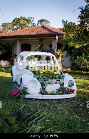 A vertical shot of a white vintage car decorated with flowers in a garden Stock Photo