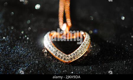 A selective focus shot of a heart-shaped gold plated pendant lined with diamonds Stock Photo