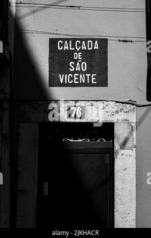 A vertical grayscale shot of a house door in Lisbon, Calcada de Sao Vicente Stock Photo