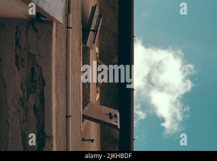 A vertical flipped shot of open wooden windows of a building in cloudy sky background Stock Photo