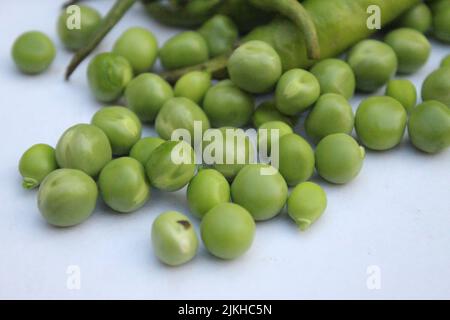 A closeup of fresh green pea seeds scattered on white background Banque D'Images
