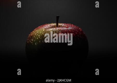 A close-up shot of a wet apple in the dark Banque D'Images