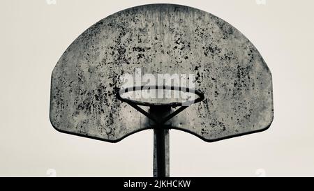 A grayscale closeup shot of a vintage basketball rim and a backboard with no net Stock Photo