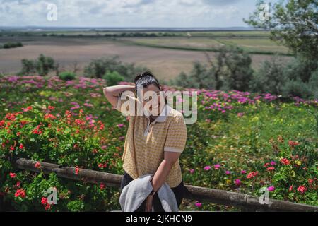 Photo d'une jeune femme caucasienne souriante qui se pose devant les fleurs Banque D'Images