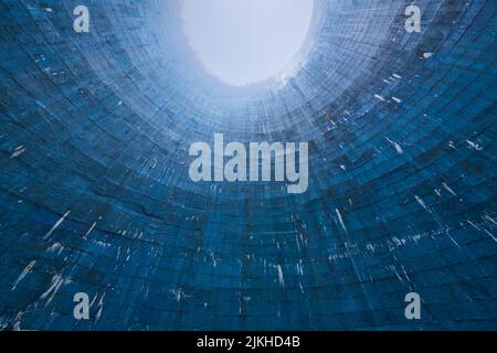 A low angle futuristic shot of a blue cooling tower in abandoned power plant Stock Photo