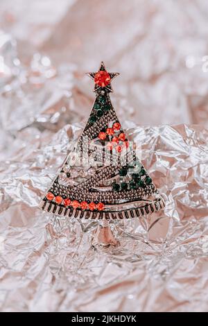 A vertical top view of cute Christmas brooch on shiny foil surface Stock Photo