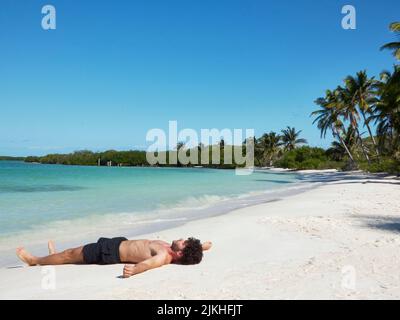 homme solitaire allongé sur une plage paradisiaque très détendu Banque D'Images