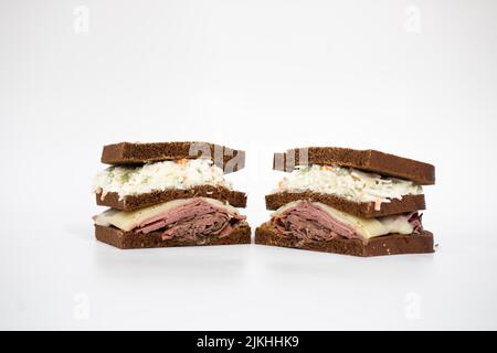 A pastrami sandwich sliced in half portraying all of its ingredients on a white background Stock Photo