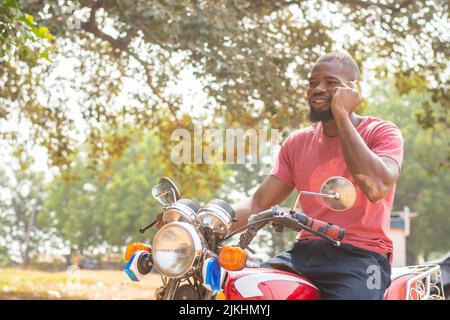 homme africain sur un vélo faisant un appel téléphonique Banque D'Images