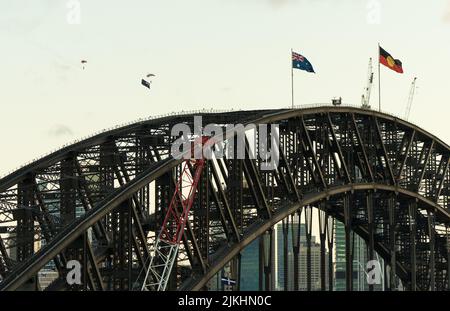 an Australian Flag and Aboriginal Flag over Sydney Harbour Bridge with Parachuters. Banque D'Images