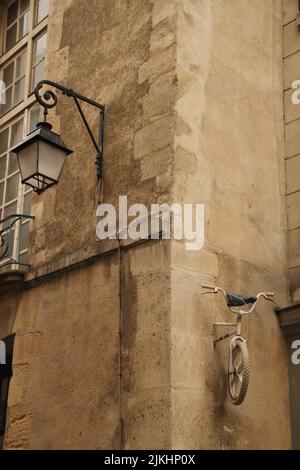 A vertical shot of an old building with lamp and half bike attached on a wall in Paris, France Stock Photo