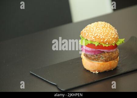 A delicious mini hamburger on a black plate on a black table with space for text Stock Photo