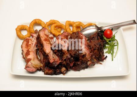 A closeup shot of the delicious sliced meat with onion rings on the white plate Stock Photo