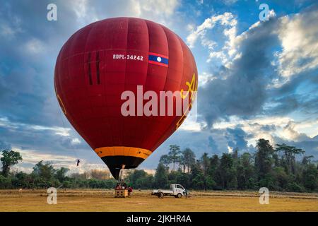 A large, red hot air balloon  with the flag of Laos preparing for a flight in Vang Vieng Stock Photo