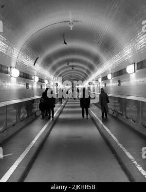 A grayscale view of people walking in St. Pauli Elbe Tunnel, Alter Elbtunnel in Hamburg, Germany Stock Photo