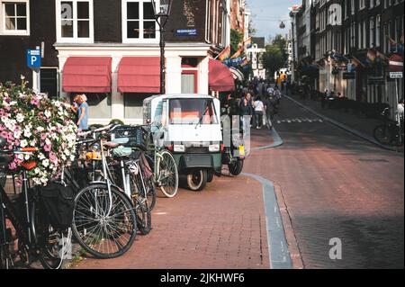 Une belle photo d'une rue à Amsterdam avec des véhicules garés sur un trottoir et des personnes marchant Banque D'Images