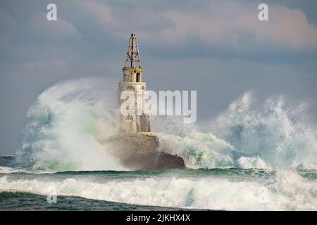 Huge waves crashing on the rocks of Ahtopol lighthouse, Bulgarian Black Sea Coast on a cloudy day Stock Photo