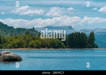 A mesmerizing seascape view surrounded by high dense trees and mountains in the background Stock Photo