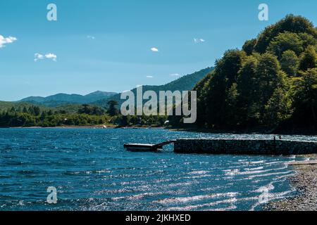 A mesmerizing seascape view surrounded by high dense trees and mountains in the background Stock Photo