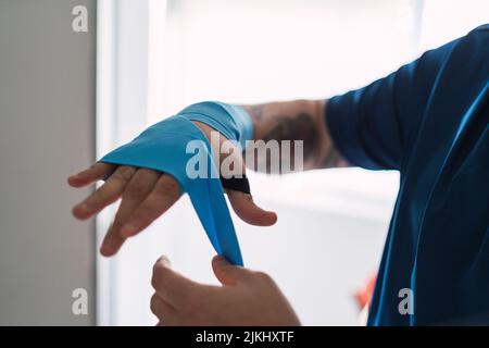 Un homme mettant des élastiques bleus sur sa main, se préparant à faire du sport Banque D'Images