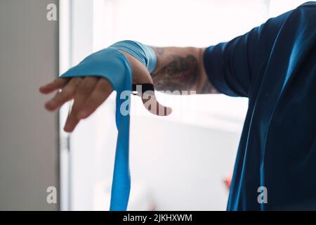 Un homme mettant des élastiques bleus sur sa main, se préparant à faire du sport Banque D'Images
