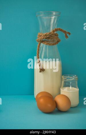 Différents produits laitiers sur fond bleu : yaourt, fromage, lait et œufs. Vitamines hydrosolubles (B1, B2, niacine et acide folique) et liposolubles v Banque D'Images