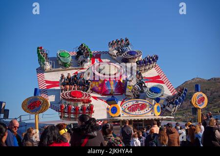 People enjoy fairground ride on 'Take Off' carousel spinning in a sharp tilt at the Birds Euroshow Funfair in Bray Seafront on sunny day. Stock Photo