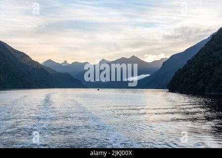 Le soleil se lève sur le Doubtful Sound, les nuages s'accrochant sur les montagnes, l'île du Sud de la Nouvelle-Zélande Banque D'Images