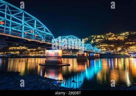 A low angle shot of an illuminated blue bridge over water in Lanzhou, China Stock Photo