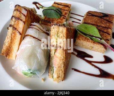 Petits sandwiches sans gluten et rouleaux de papier de riz sur une assiette blanche Banque D'Images