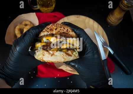 A man's hands in black rubber gloves holding tasty burger Stock Photo