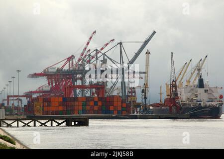 The cranes and cargo boxes near a boat on the harbor on the Tejo River in Lisbon, Portugal Stock Photo