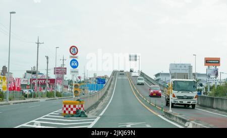 A row of cars driving over a small bridge in Okinawa, Japan Stock Photo