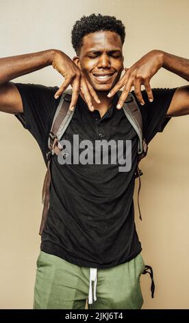 Photo verticale d'un homme afro-américain avec un sac à dos posé sur l'appareil photo. Banque D'Images