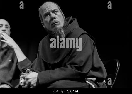 A man with a beard sitting on a chair at a discussion against hatred between all holy religions indoor. Black and white Stock Photo