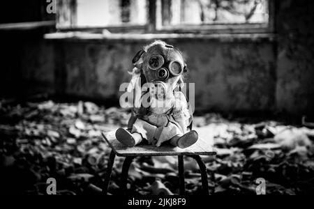 Une photo en échelle de gris d'une poupée créepy avec un masque à gaz respiratoire dans un bâtiment abandonné Banque D'Images