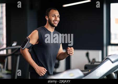 Portrait de l'athlète masculin noir élégant s'exerçant sur un tapis roulant à la salle de gym Banque D'Images