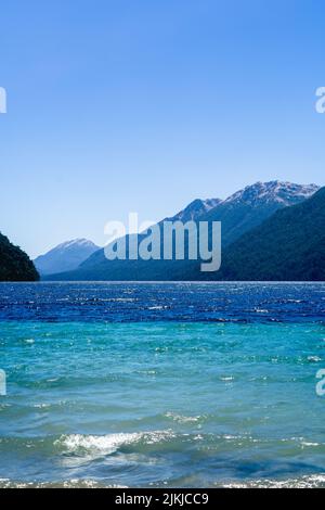 A beautiful shot of the calm clear sea surrounded by greenery-covered hills and mountains Stock Photo