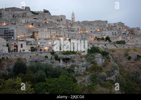 A scenic view of Sassi of Matera cave settlements on a green hill in Italy at sunset Stock Photo