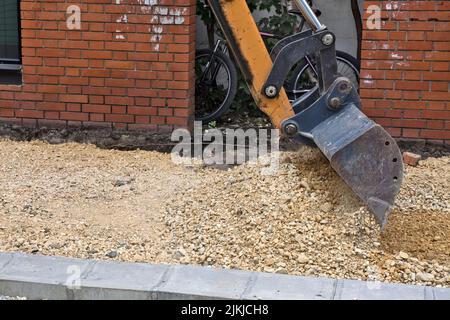 La pelle hydraulique travaille sur la rue et prépare le sol pour la pose d'asphalte ou de dalles. Banque D'Images
