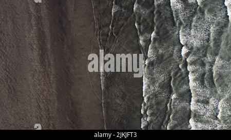 A drone shot of the foamy waves of the sea touching the sandy shore, Murud Janjira, India Stock Photo