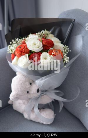 Un adorable ours en peluche et un bouquet de fleurs Banque D'Images