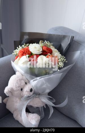 Un adorable ours en peluche et un bouquet de fleurs Banque D'Images